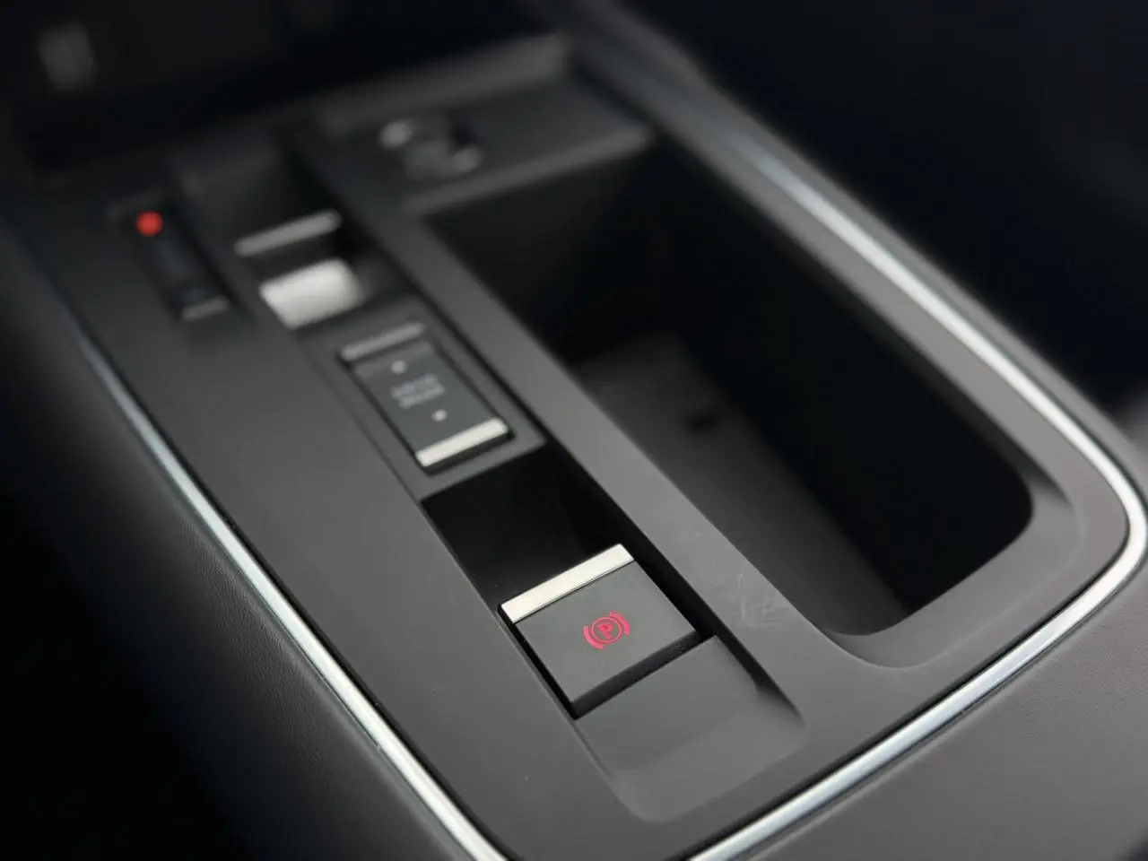 Gros plan sur la console centrale noire du Citroën C5 Aircross avec bouton de frein de stationnement électrique éclairé en rouge.