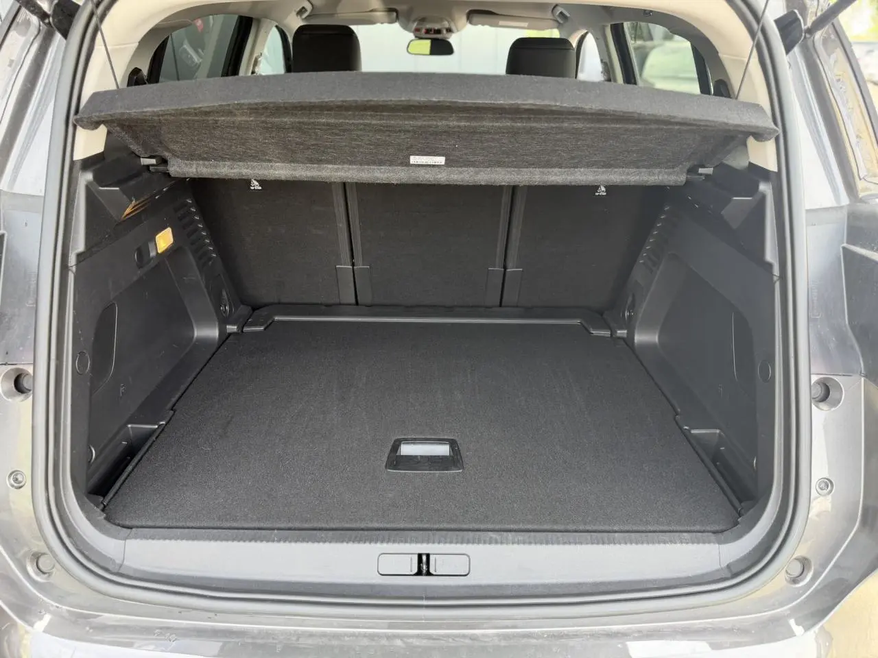 Coffre ouvert vu de l’arrière d’un Citroën C5 Aircross gris Platinium, avec plage arrière relevée et intérieur noir.