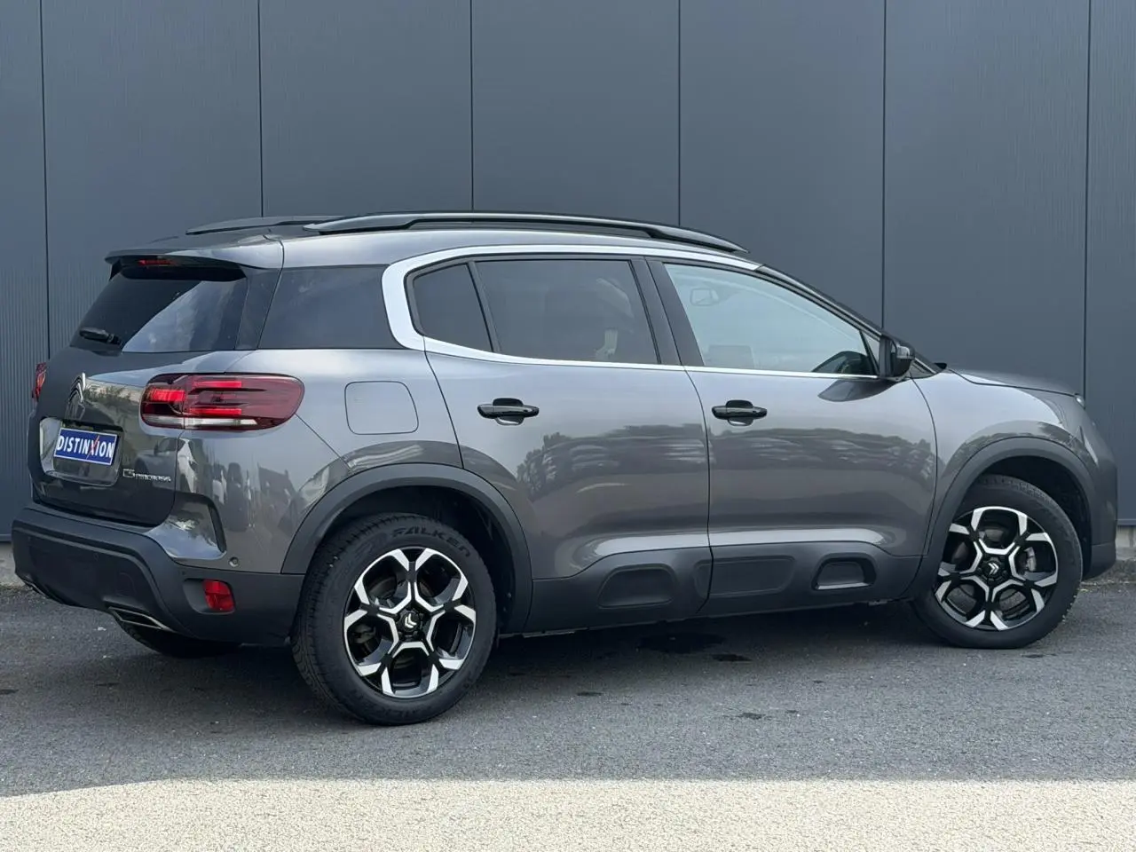 Vue de profil droit du Citroën C5 Aircross gris Platinium avec jantes alliage 18 pouces et barres de toit noires.