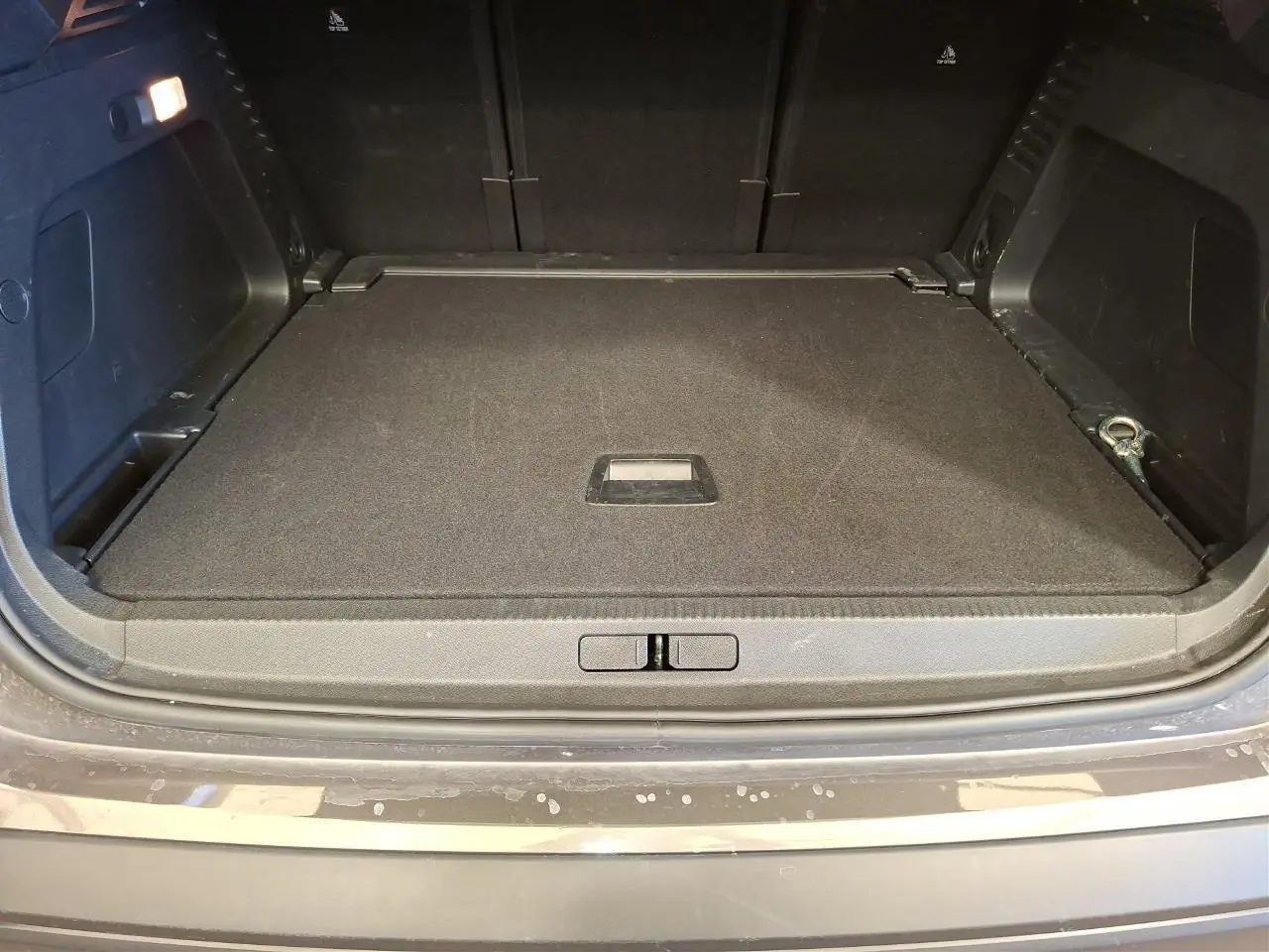 Vue du coffre ouvert du Citroën C5 Aircross gris Platinium, montrant le plancher plat et les rangements latéraux.