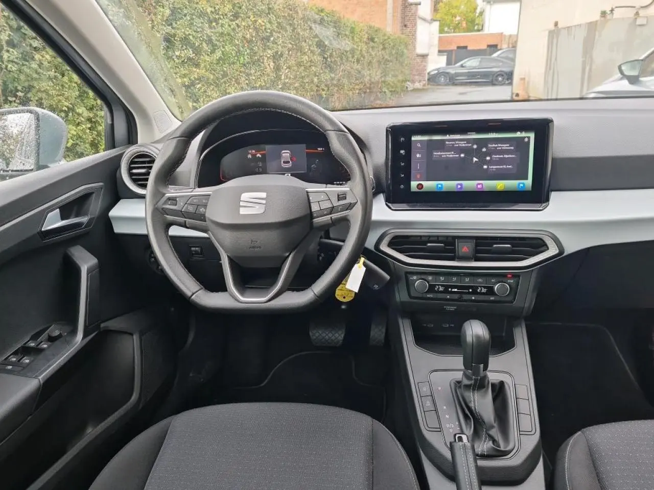 Vue intérieure frontale du poste de conduite de la SEAT Ibiza 2024 avec volant cuir multifonction et écran tactile GPS.