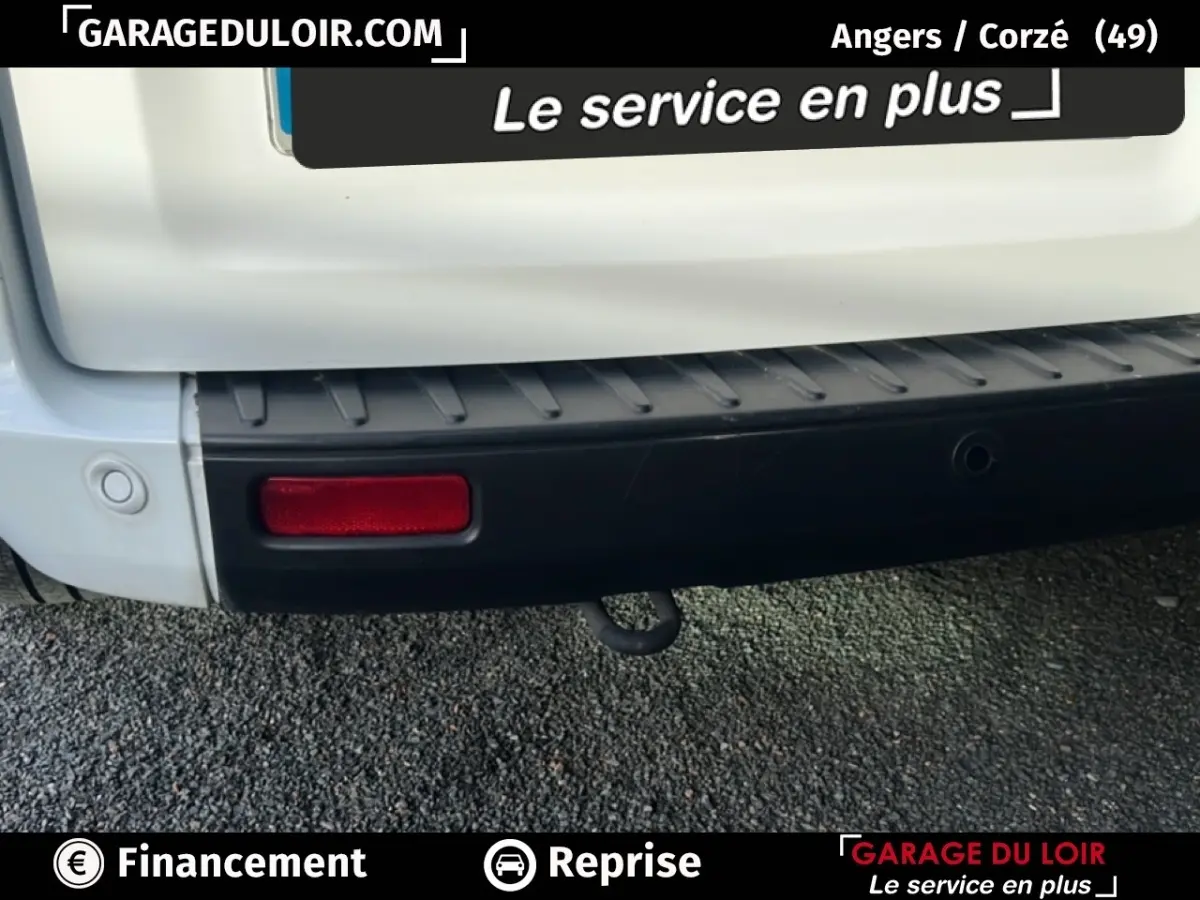 Gros plan sur le pare-chocs arrière noir et blanc du Ford Transit Custom Fourgon avec feu rouge et crochet d'attelage visible.