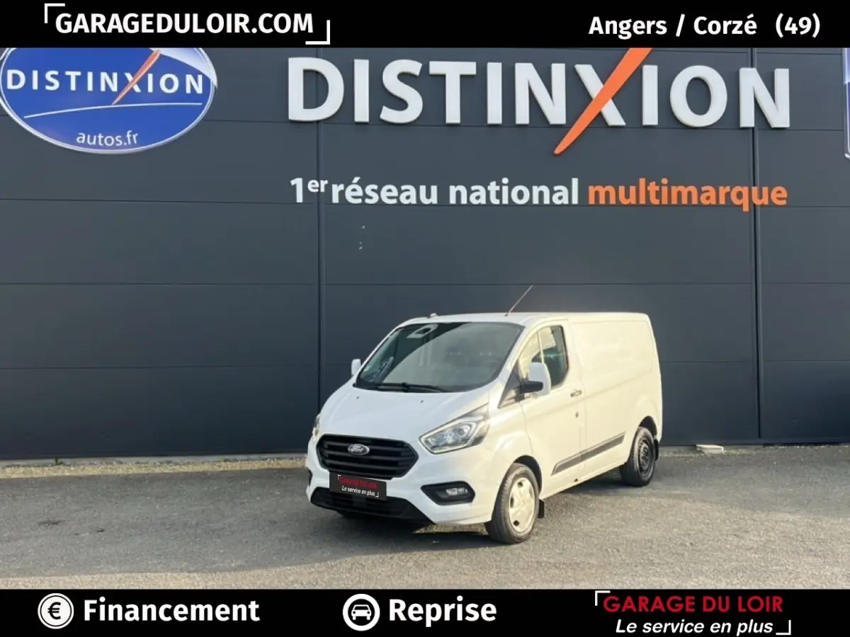Ford Transit Custom Fourgon blanc en 3/4 avant droit, stationné devant un mur gris avec logo Distinxion.