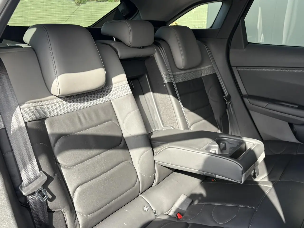 Vue intérieure sur les sièges arrière en cuir gris avec accoudoir central déployé de la Citroën C5 X 2024.