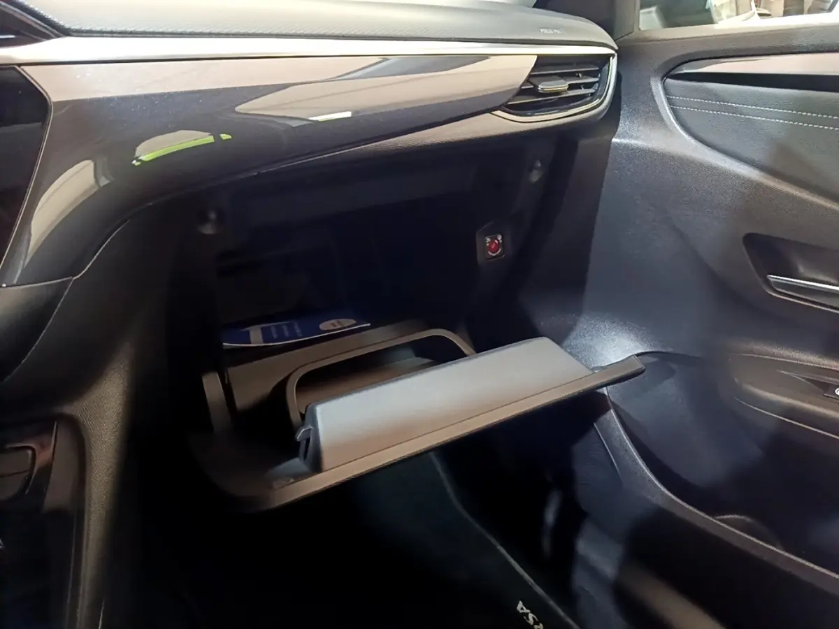 Vue intérieure côté passager de la boîte à gants ouverte de l’Opel Corsa blanche 2023 avec tableau de bord noir brillant.