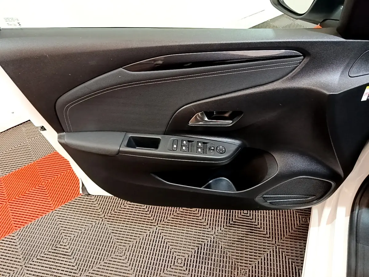 Vue rapprochée de la porte avant gauche noire d'une Opel Corsa blanche, avec commandes électriques et haut-parleur intégré.