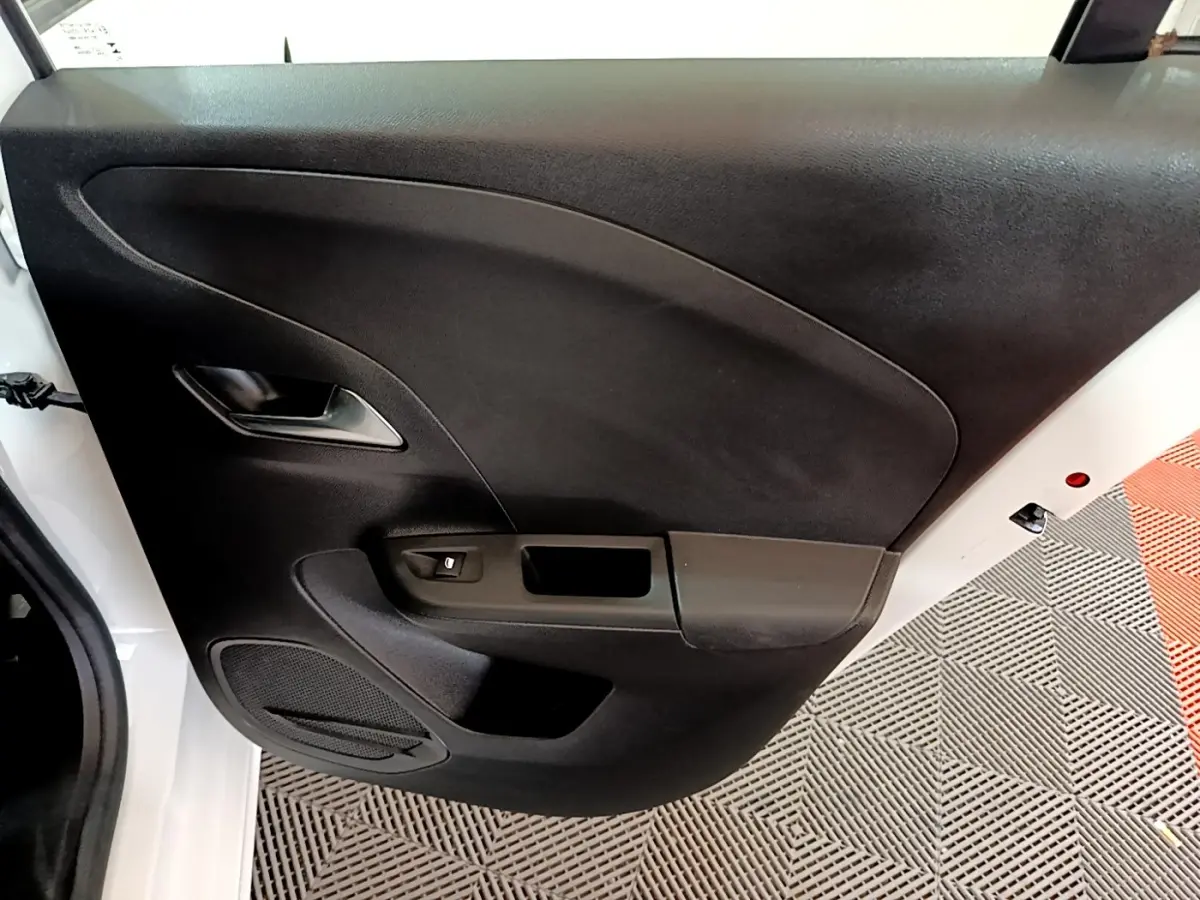 Vue rapprochée de la porte arrière gauche noire d'une Opel Corsa blanche, avec poignée et haut-parleur intégrés.