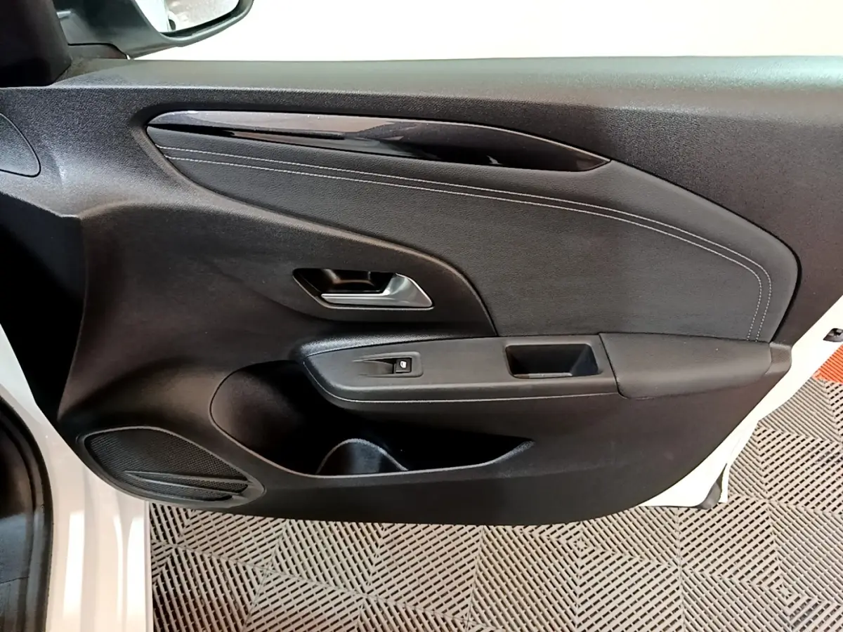 Vue rapprochée de la porte avant gauche noire de l’Opel Corsa blanche 2023, avec poignée et commande de vitre électrique.