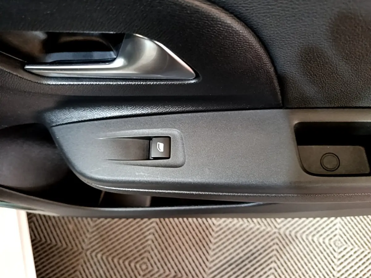 Détail de la porte côté gauche de l’Opel Corsa blanche 2023, avec poignée argentée et bouton de lève-vitre.