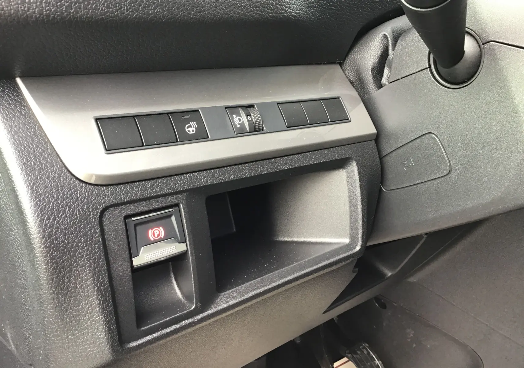 Gros plan sur la console côté gauche du tableau de bord noir du Peugeot Expert Cabine Approfondie avec bouton frein à main électronique.