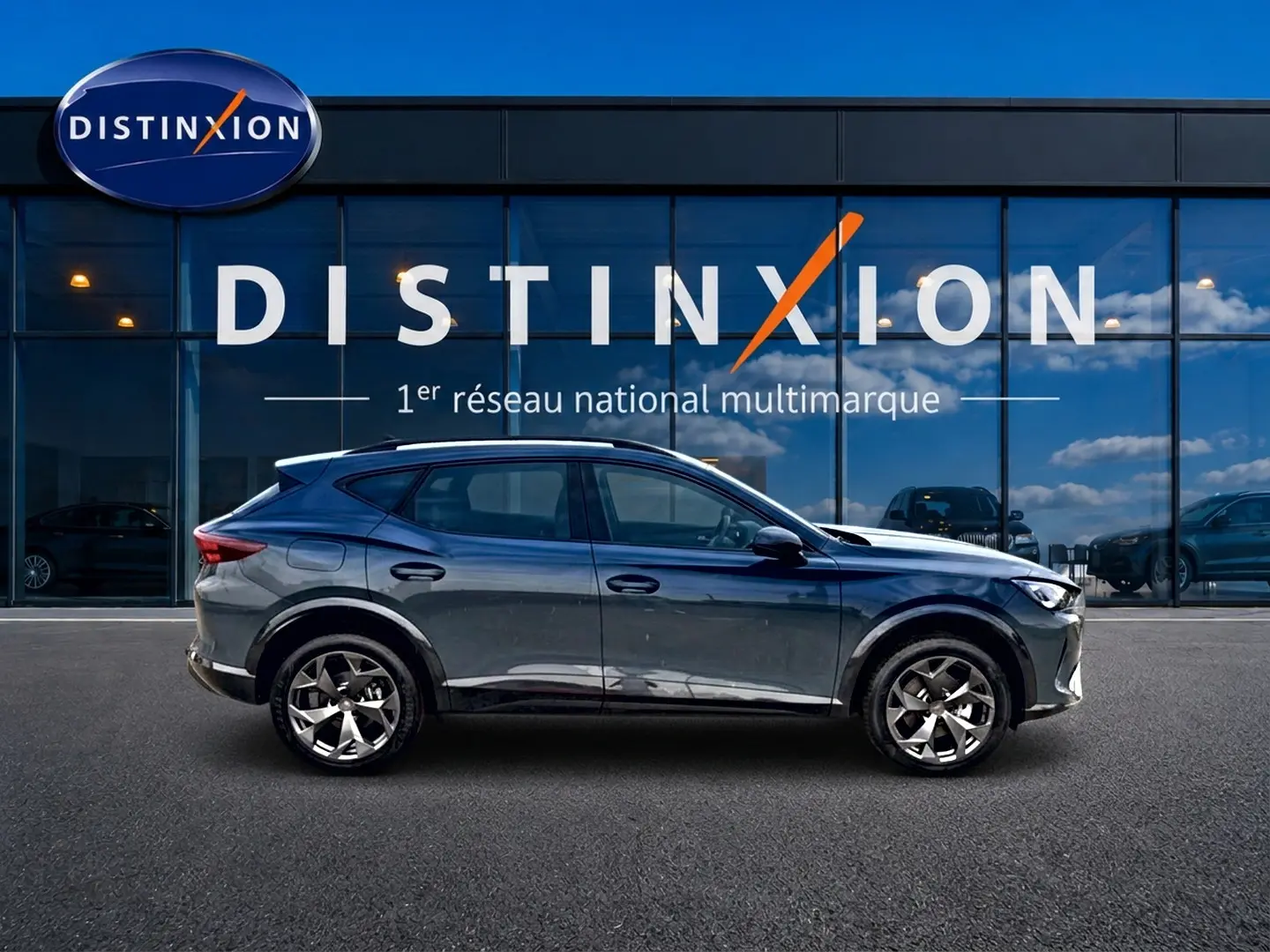 Vue de profil côté gauche du CUPRA Formentor 1.5 etsi hybrid 150 DSG7 en bleu fjord devant une vitrine Distinxion.