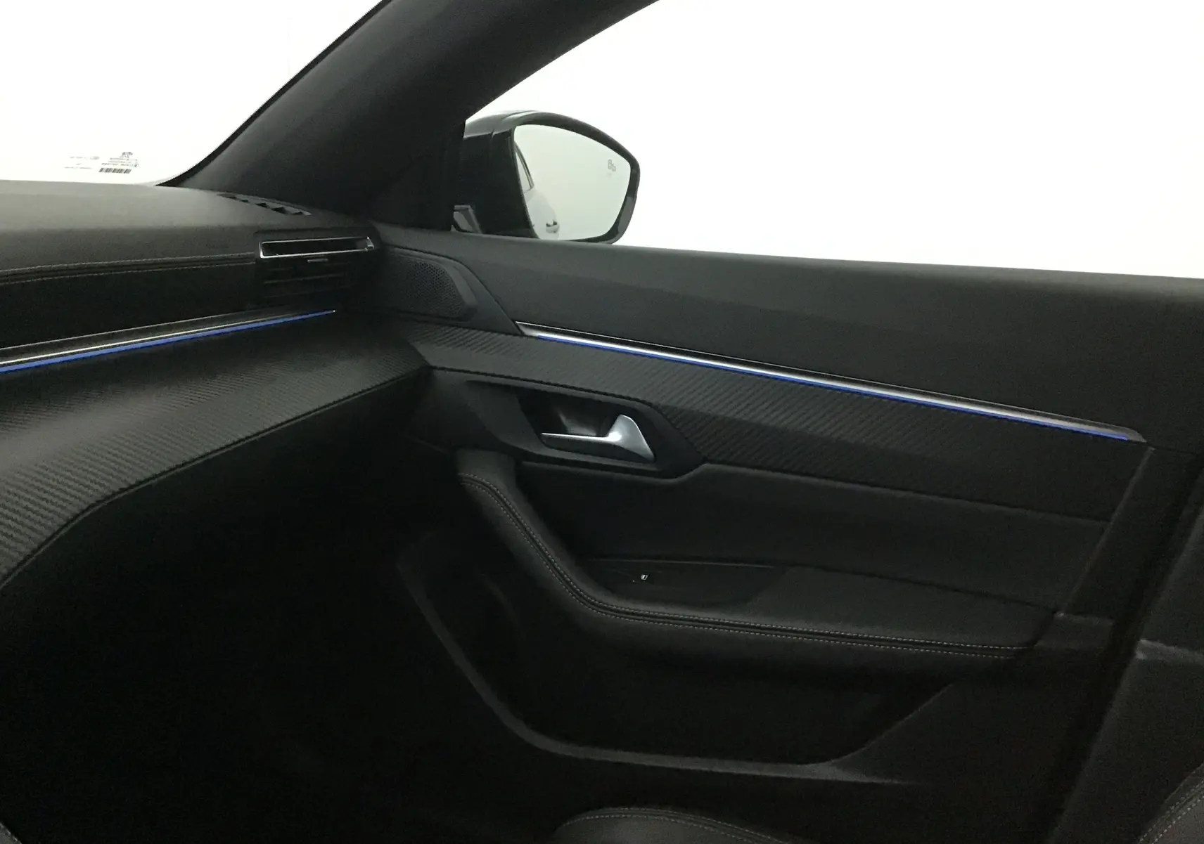 Intérieur côté passager du Peugeot 508 SW 2024 avec garniture noire et bande lumineuse bleue intégrée à la porte.