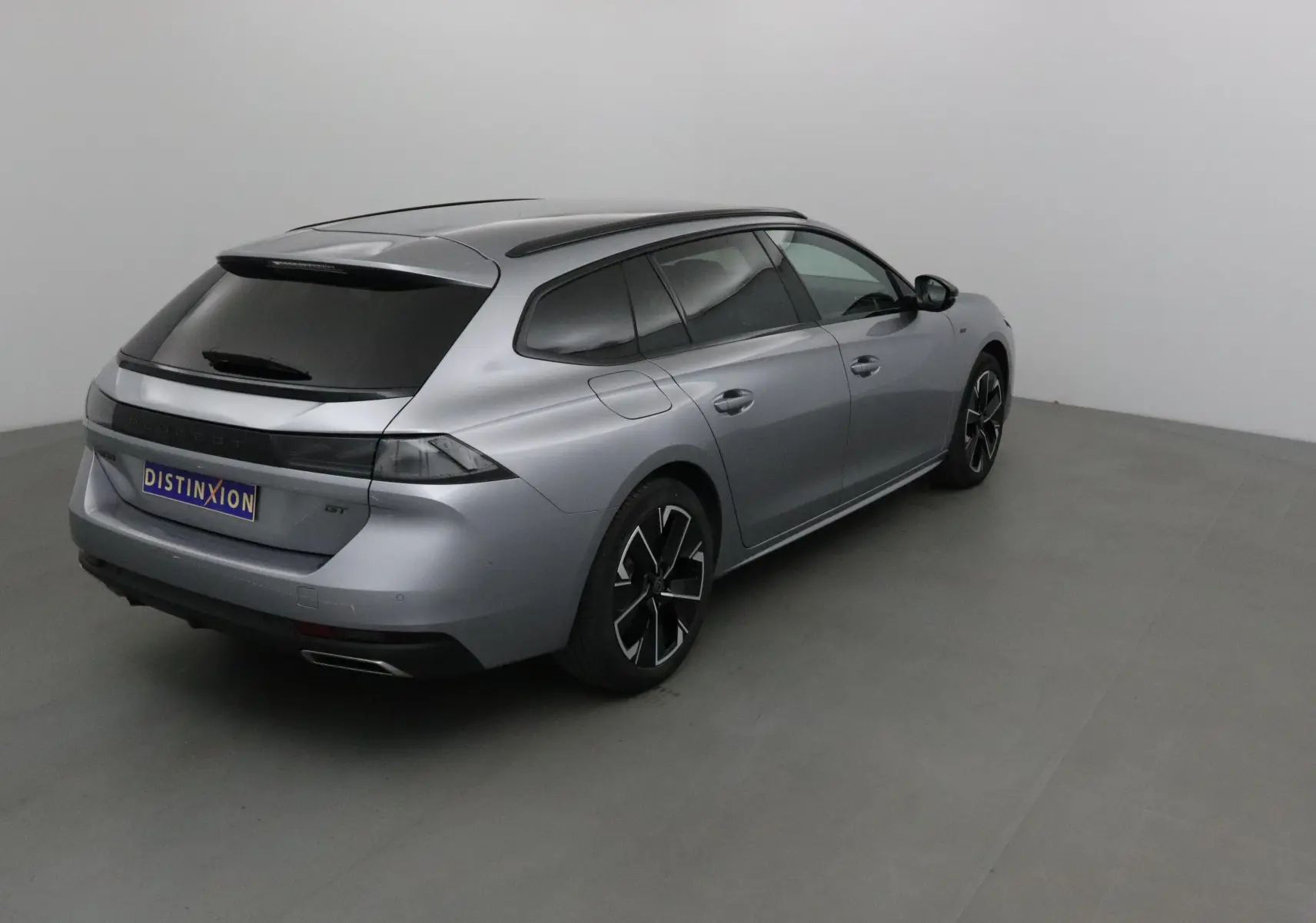 Peugeot 508 SW gris Artense vue 3/4 arrière droit, avec vitres teintées et jantes noires distinctives.