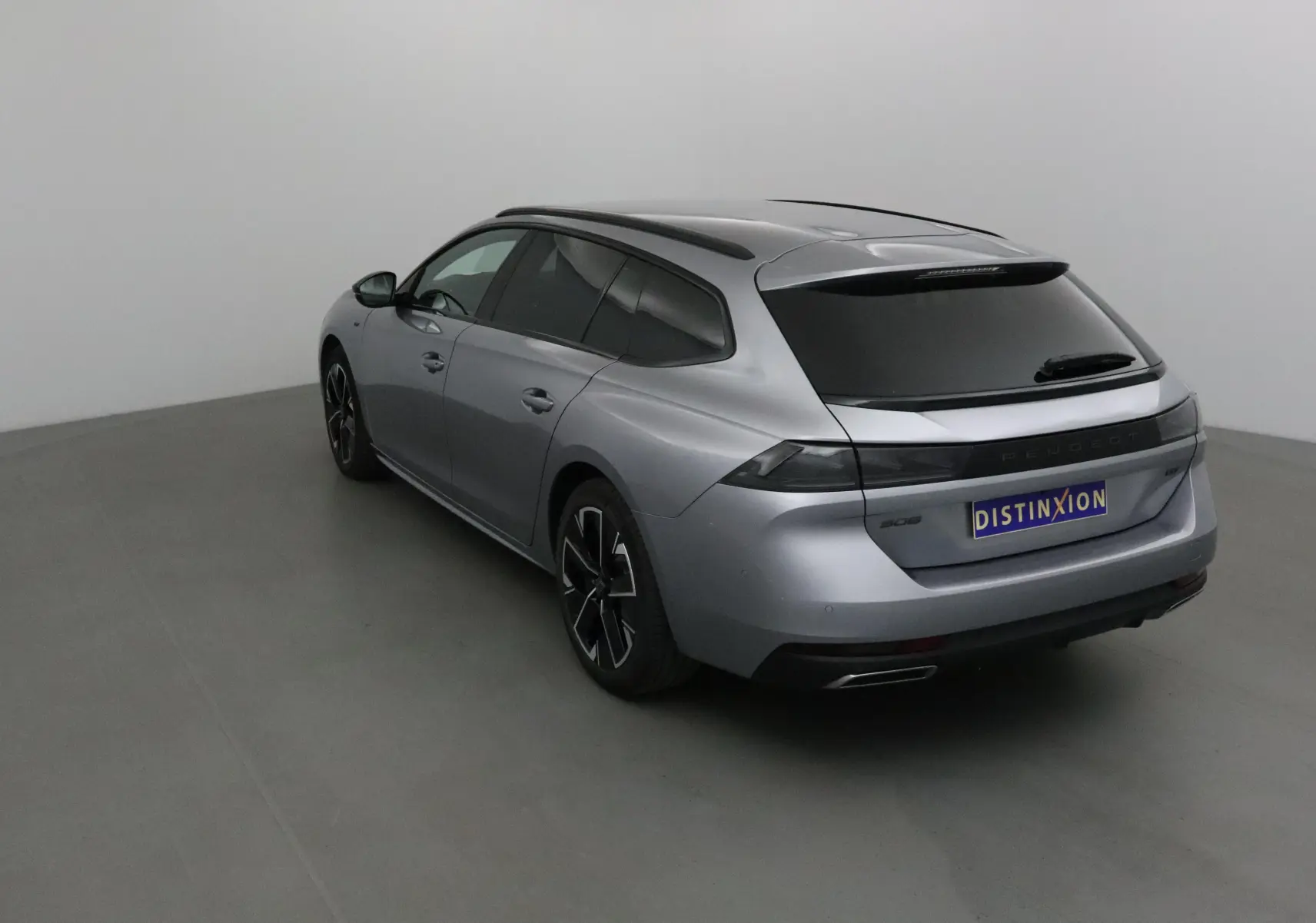 Peugeot 508 SW gris Artense vue 3/4 arrière droit, avec vitres teintées et jantes noires distinctives.