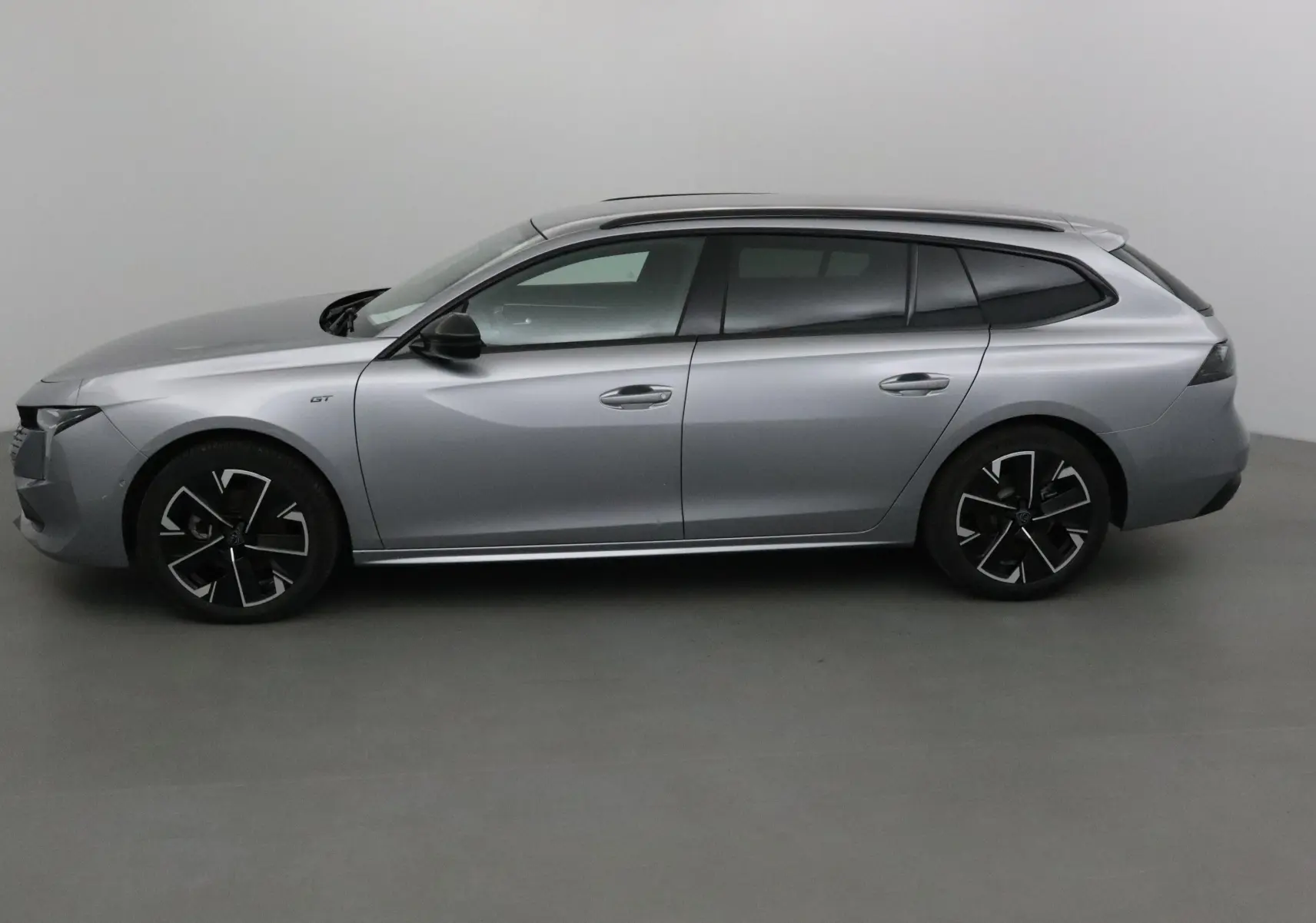 Profil côté gauche d'une Peugeot 508 SW gris Artense 2024 avec jantes noires et badge GT visible.