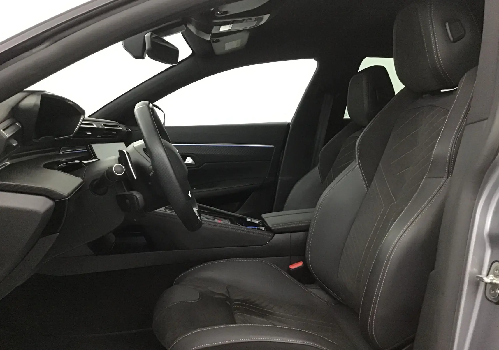 Intérieur côté conducteur de la Peugeot 508 SW 2024 gris Artense, sièges cuir et tableau de bord moderne.