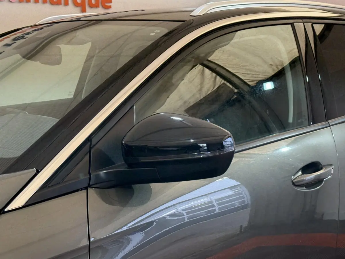 Gros plan sur le rétroviseur côté conducteur d’un Peugeot 3008 vert, avec reflet sur la portière avant.