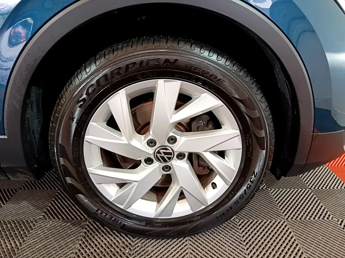 Gros plan sur la roue avant droite du Volkswagen Tiguan bleu, mettant en valeur la jante alliage et le pneu Pirelli Scorpion.