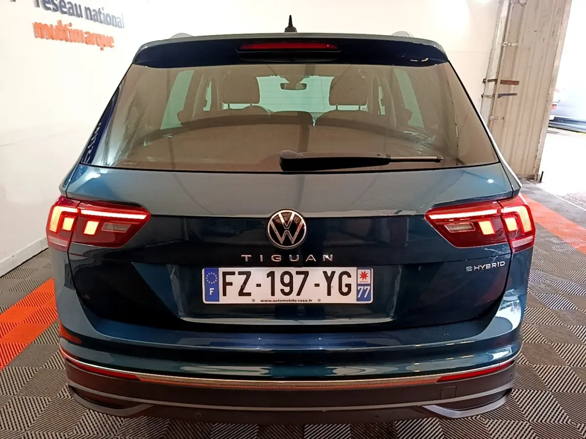 Vue arrière d'un Volkswagen Tiguan bleu hybride rechargeable avec feux LED allumés et plaque d'immatriculation française.