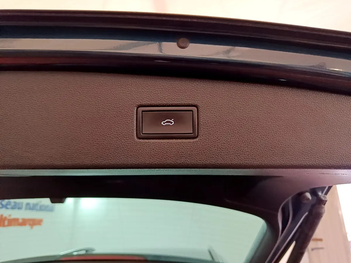 Bouton d'ouverture électrique du coffre sur la partie intérieure du hayon d'un Volkswagen Tiguan bleu.