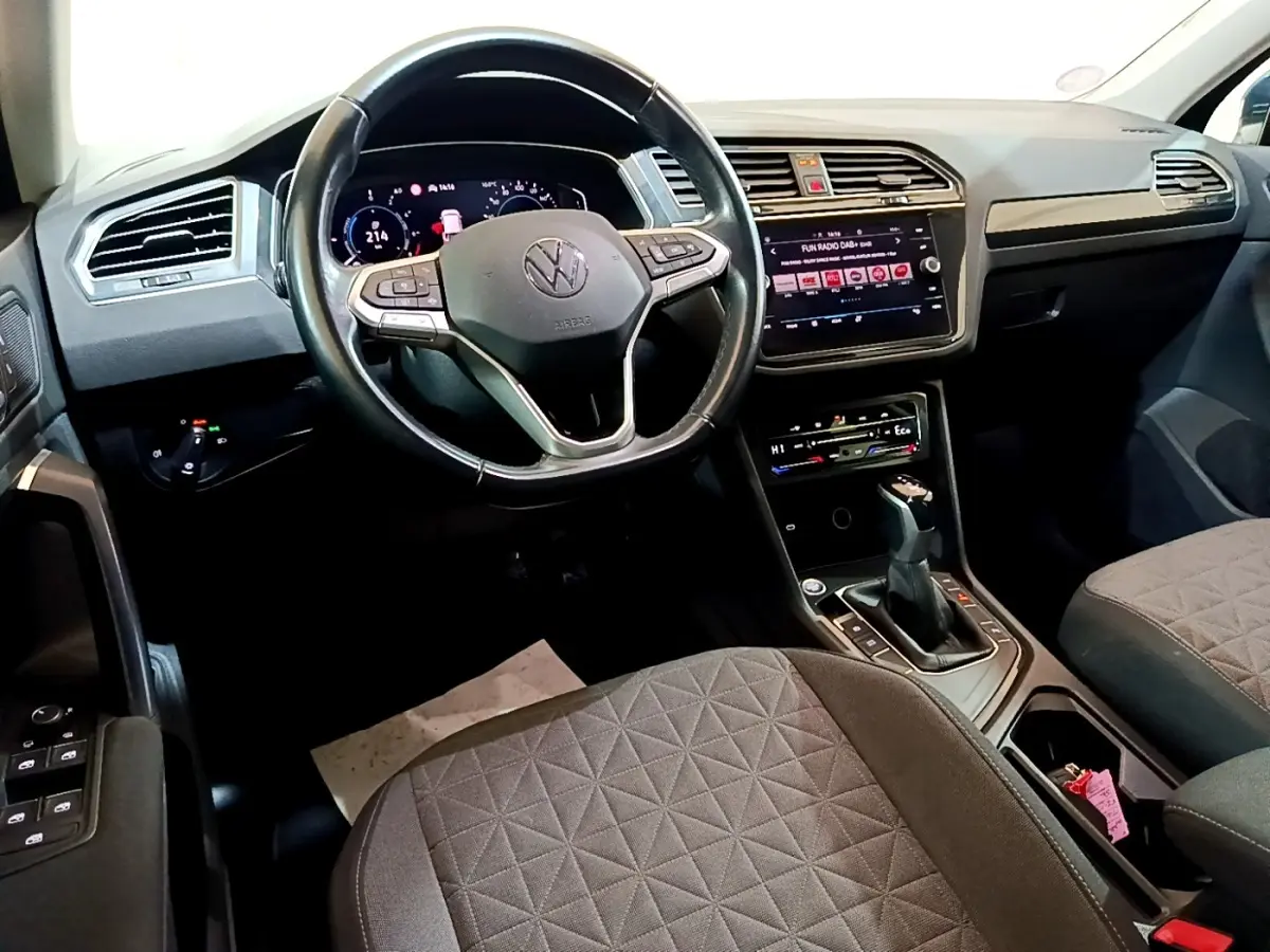 Vue intérieure avant du Volkswagen Tiguan 1.4 eHybrid 2021, volant cuir multifonctions et écran tactile central allumé.