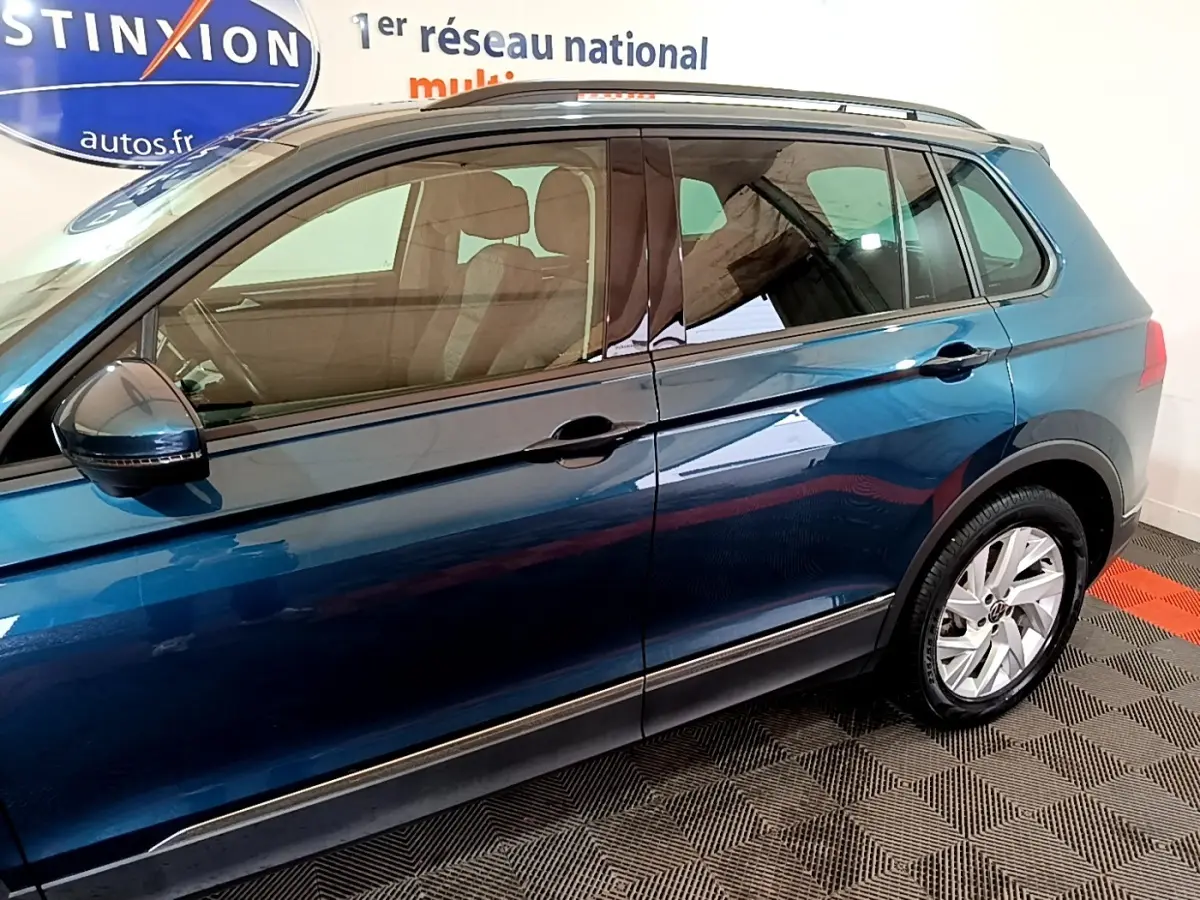 Vue latérale droite d'un Volkswagen Tiguan bleu 2021 avec jantes alliage et rétroviseurs électriques.