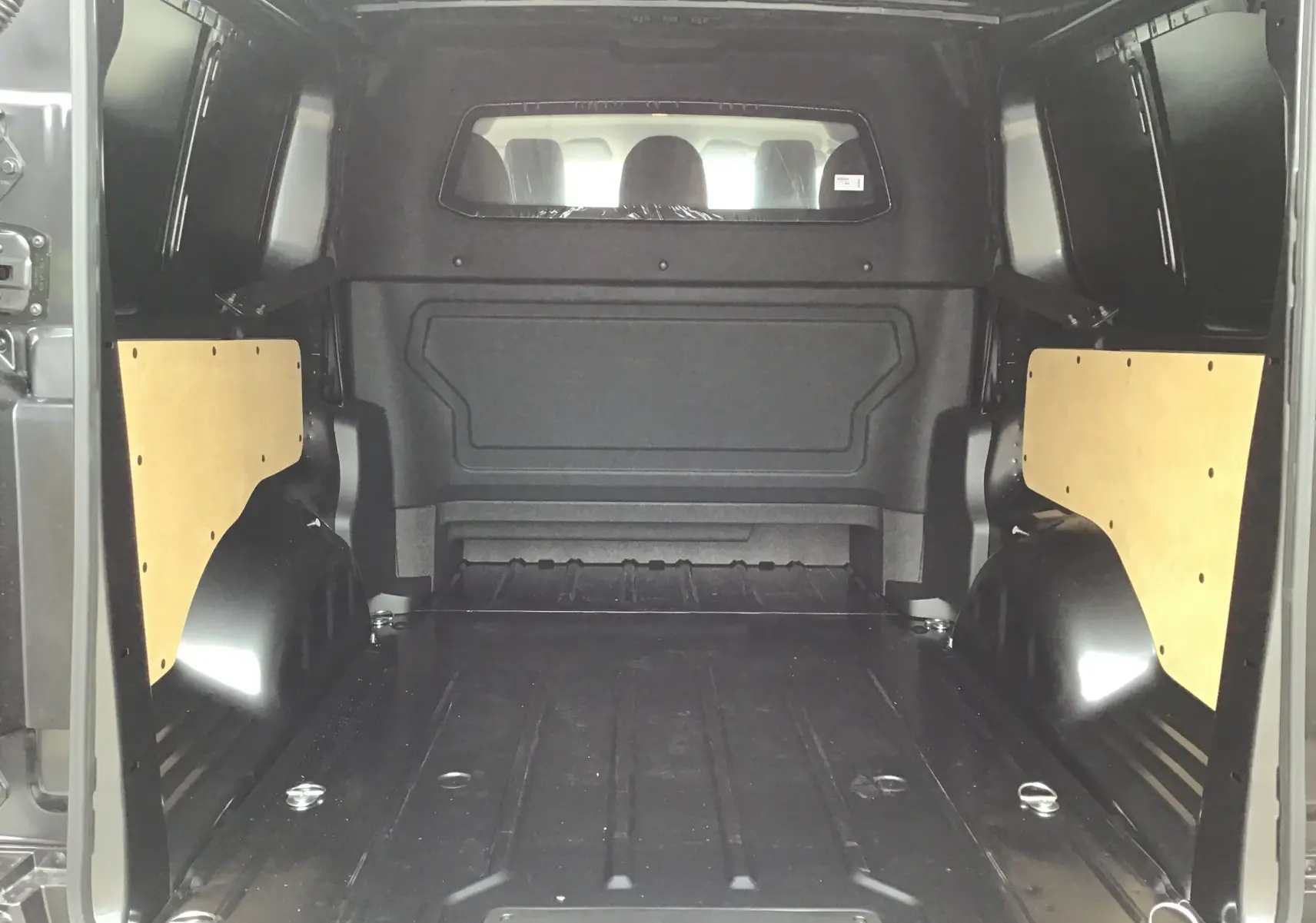 Vue intérieure arrière du Peugeot Expert XL gris titane, montrant l'espace de chargement vide avec protections latérales en bois clair.