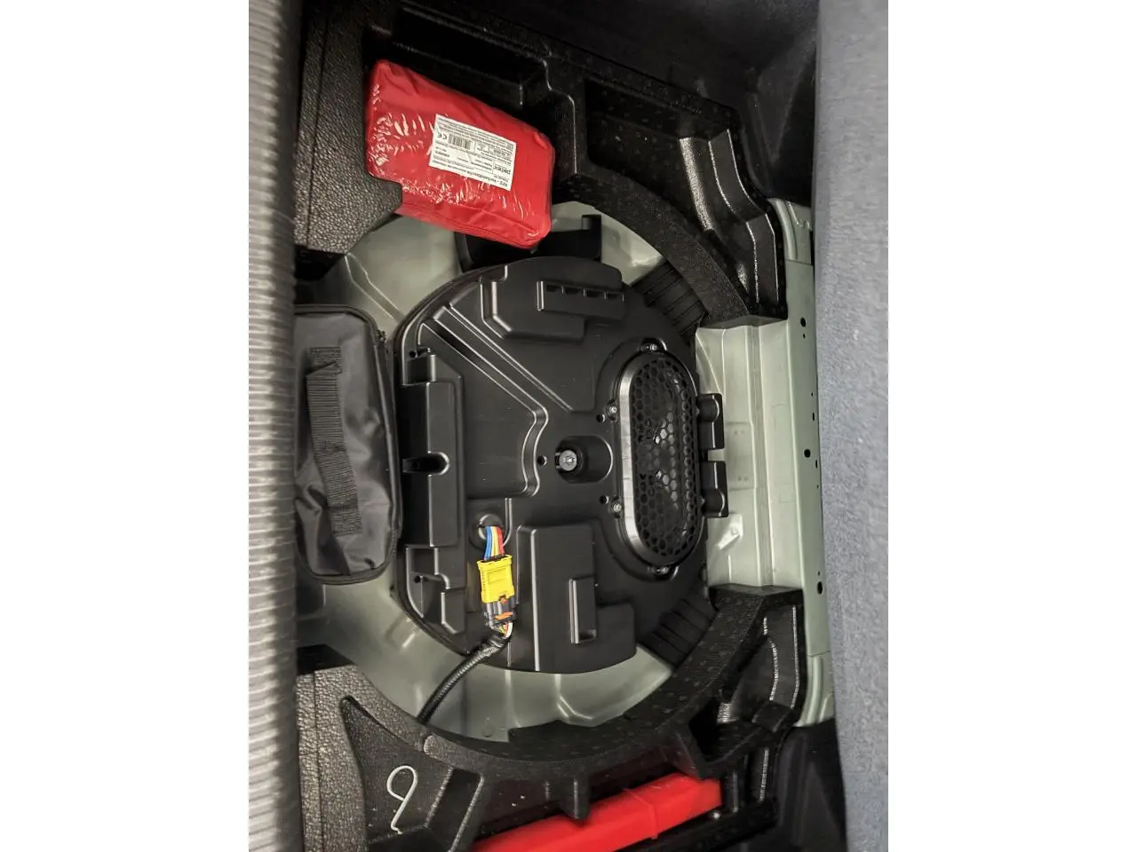 Vue rapprochée du coffre de la Peugeot 308 2024 montrant le compartiment sous plancher avec équipement de secours.