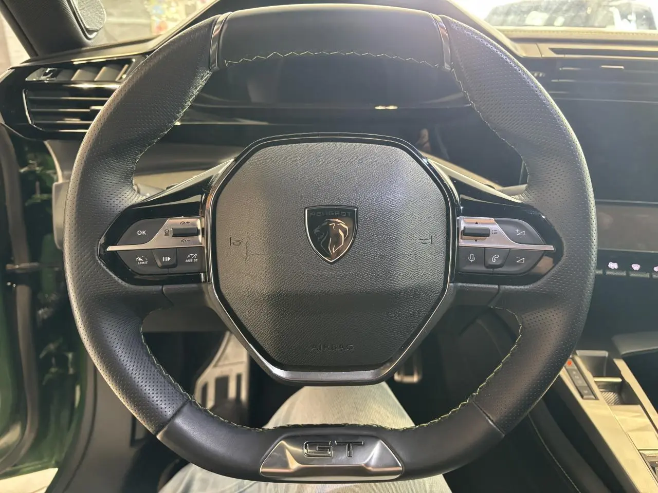 Vue rapprochée du volant cuir noir avec surpiqûres vertes et logo GT de la Peugeot 308 2024 vert.