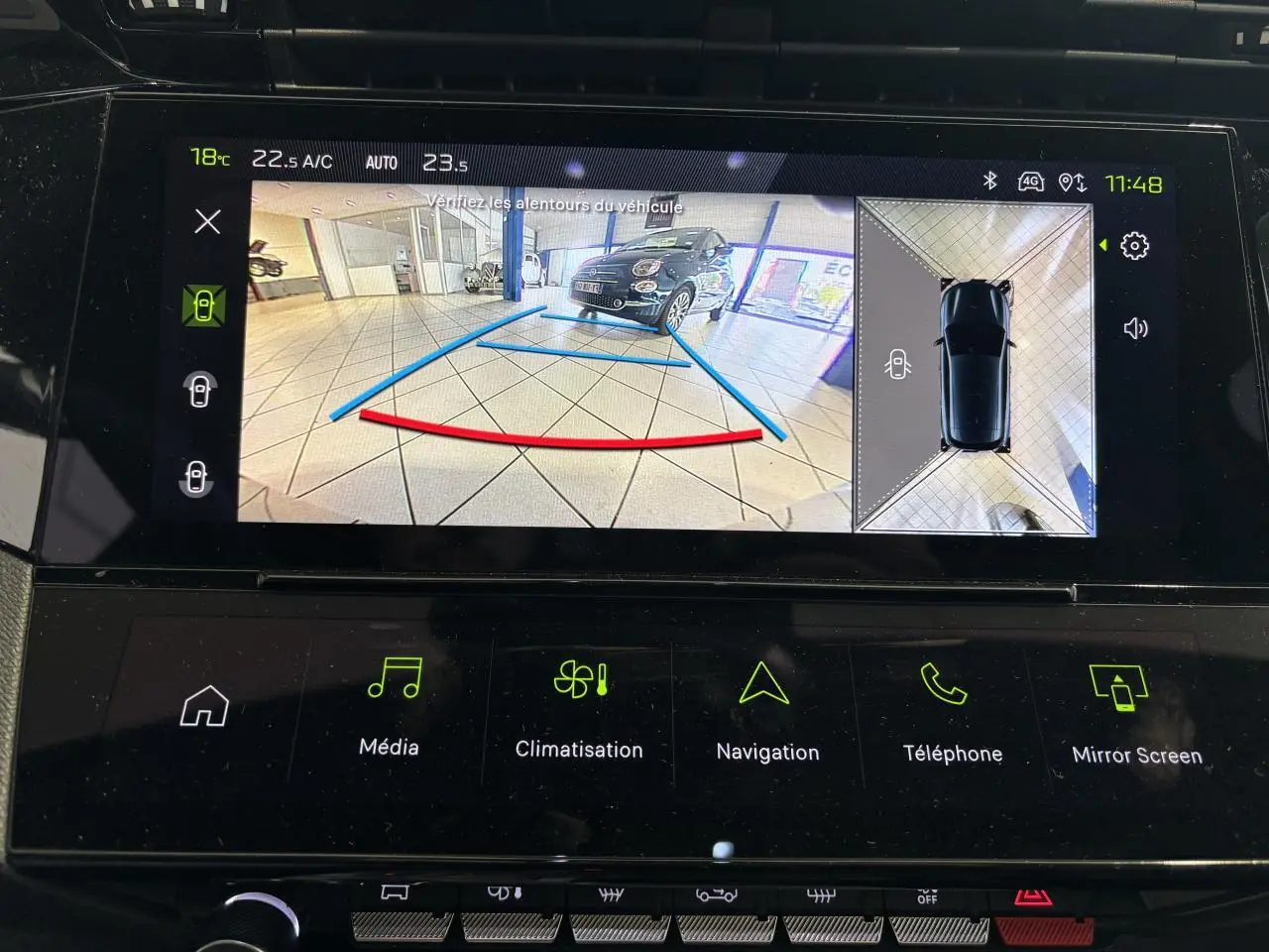 Vue écran caméra de recul avec affichage 3D et image d'une voiture noire en intérieur sur dalle carrelée.
