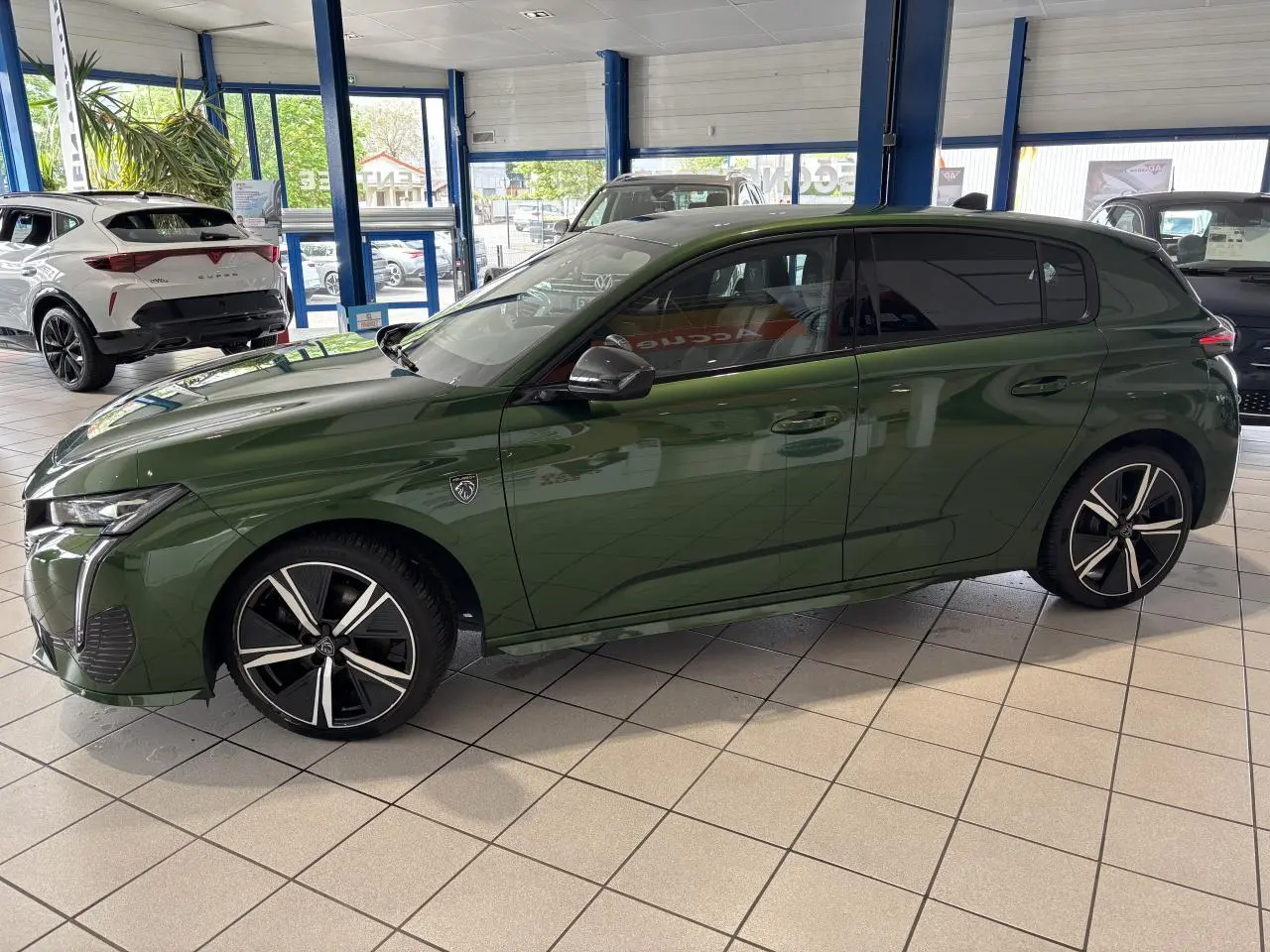Peugeot 308 GT vert vue de profil côté gauche en intérieur avec jantes alliage noires et vitres surteintées.