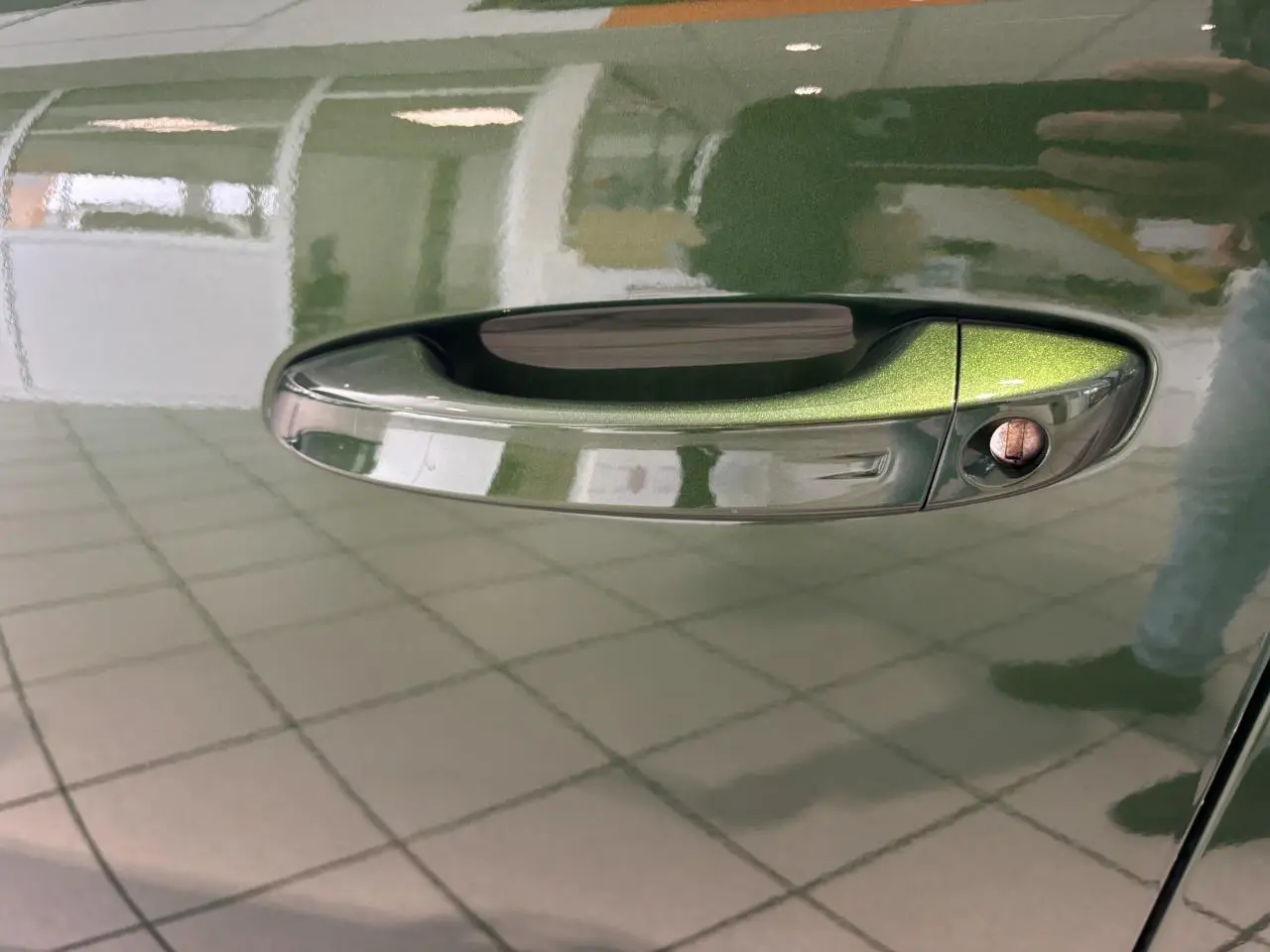 Poignée de porte côté gauche vert métallisé sur Peugeot 308 2024, reflet intérieur et serrure visible.