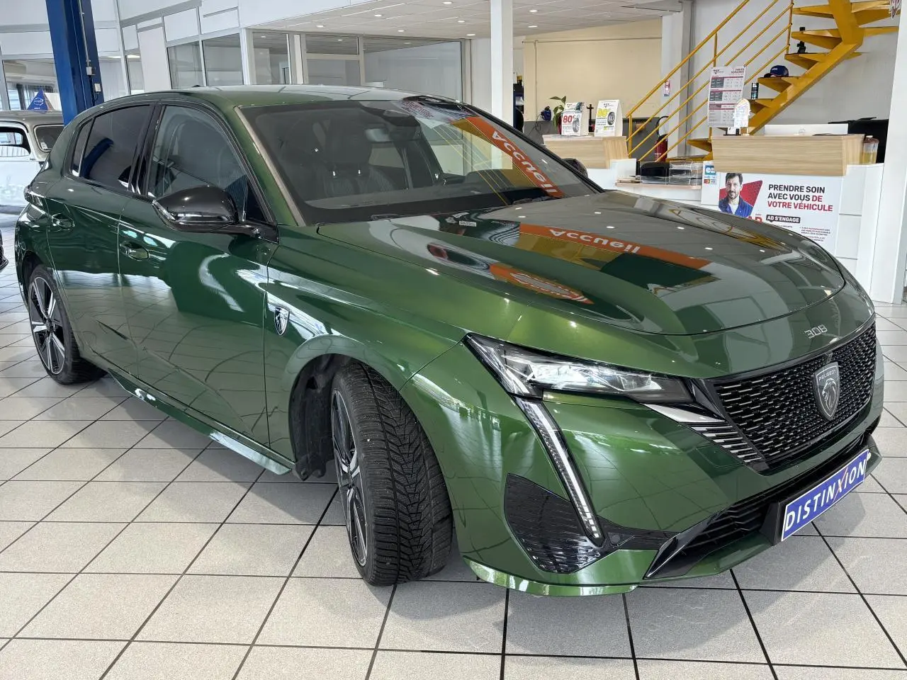 Peugeot 308 GT vert métallisé vue 3/4 avant droit, calandre noire brillante et feux LED griffés.