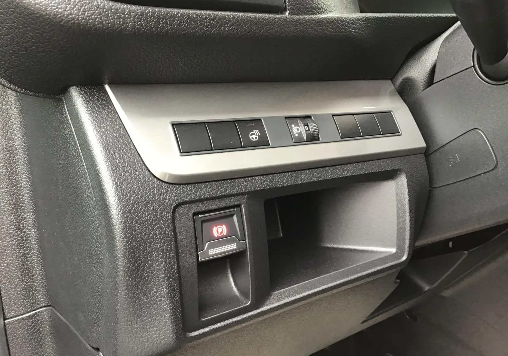 Gros plan sur la console côté conducteur du Peugeot Expert gris titane, montrant les commandes de frein à main électrique et réglage des phares.