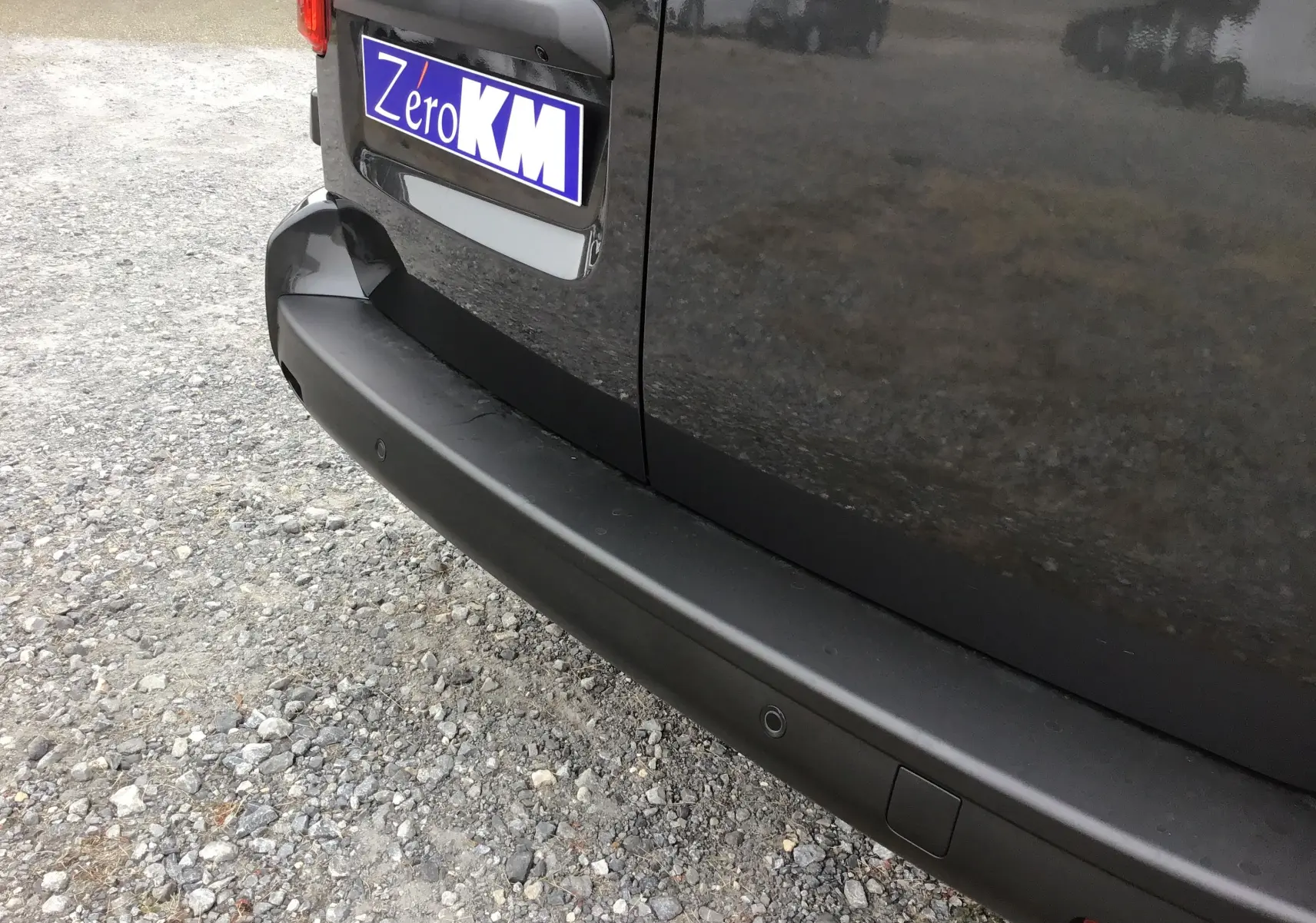 Gros plan sur le pare-chocs arrière gris titane du Peugeot Expert Cabine Approfondie avec caméra de recul visible.