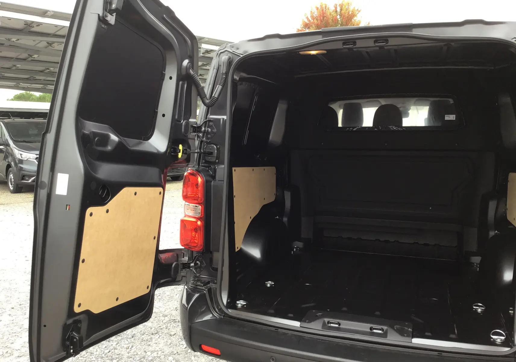 Vue arrière ouverte du Peugeot Expert XL gris titane, montrant l’espace de chargement vide avec panneaux de protection en bois.