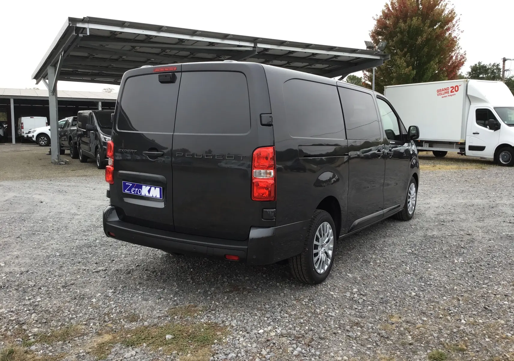 Vue 3/4 arrière droite d'un Peugeot Expert gris titane, fourgon fermé avec vitres teintées et feux arrière rouges.