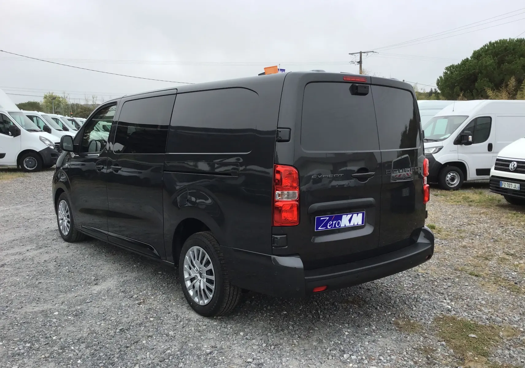 Vue 3/4 arrière droite d’un Peugeot Expert cabine approfondie gris titane avec vitres arrière teintées et feux rouges visibles.