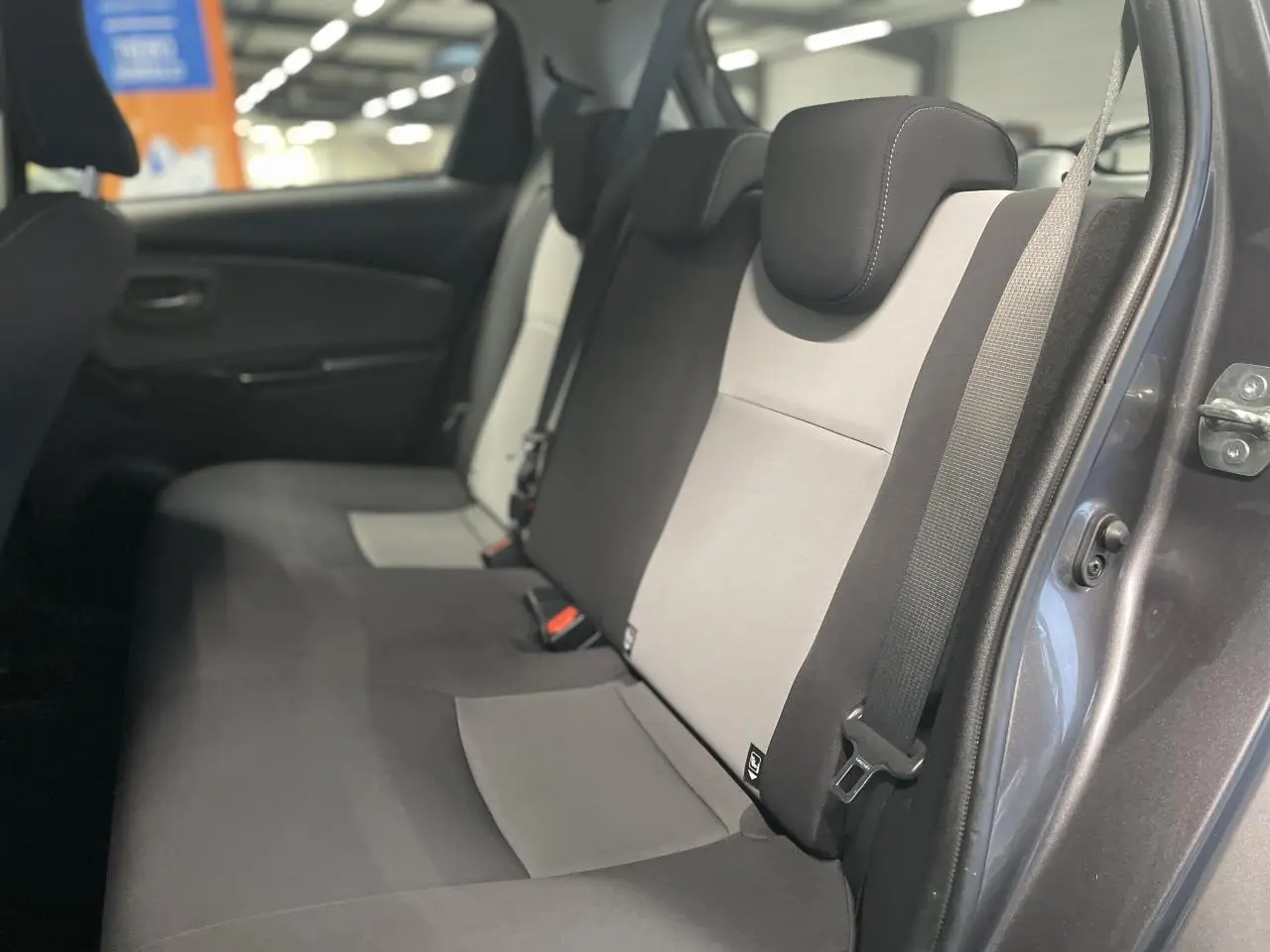 Vue intérieure côté droit sur la banquette arrière bicolore gris clair et noir d'une Toyota Yaris hybride 2020 gris foncé métallisé.