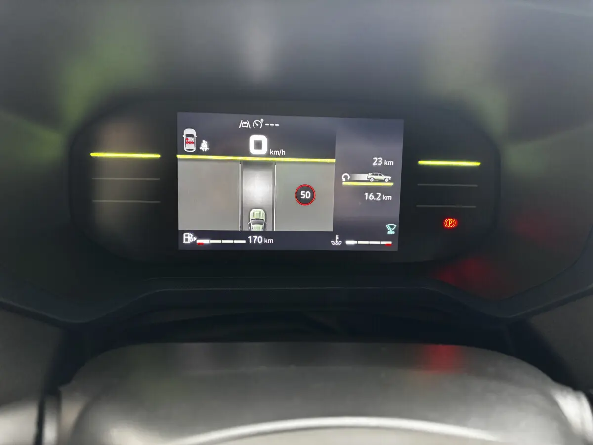 Combiné d'instruments numérique du Dacia Bigster 2025 affichant la vitesse, autonomie et alertes, vue frontale rapprochée.