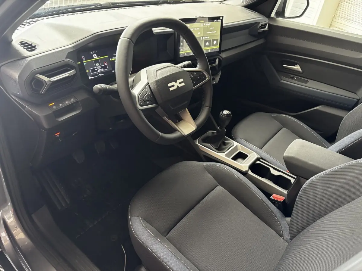 Intérieur du Dacia Bigster gris foncé, vue côté conducteur, volant multifonctions et écran tactile central visible.