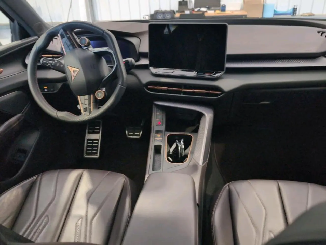 Intérieur du CUPRA TERRAMAR 1.5 e-Hybrid vu de face, avec tableau de bord noir texturé et volant sport cuir cuivré.