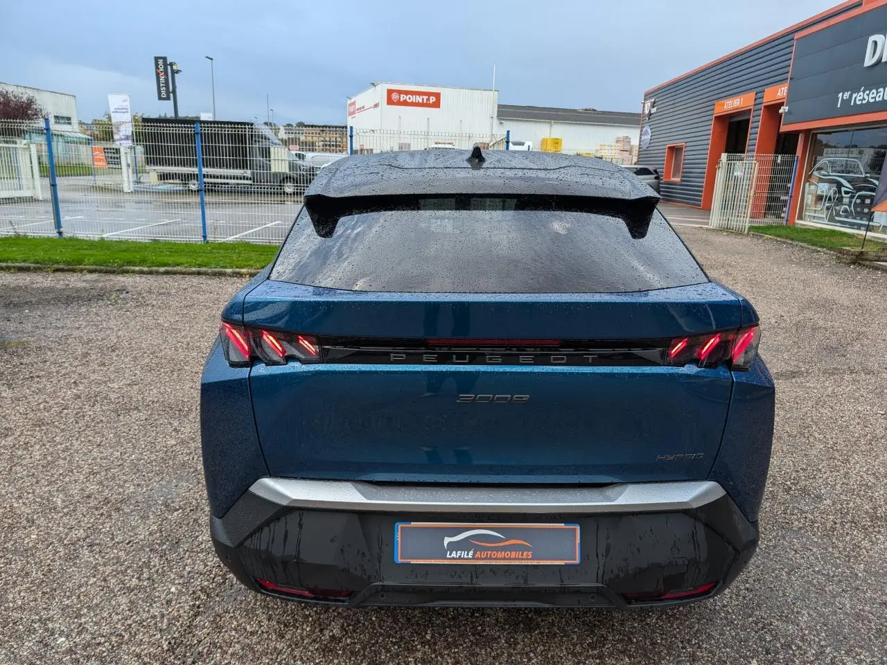 Vue arrière d’un Peugeot 3008 hybride bleu métallisé avec feux arrière à griffes LED et bandeau noir laqué.
