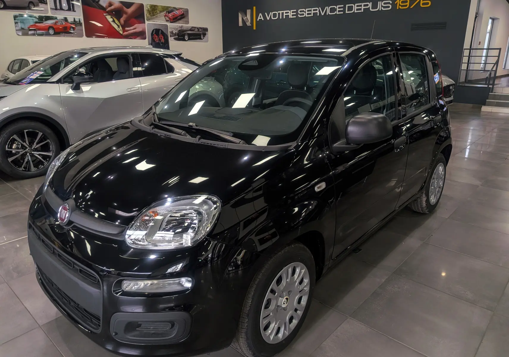 Vue 3/4 avant droite de la FIAT Panda 1.0 Hybrid 2025 en noir cinéma, compacte avec phares arrondis et jantes acier.