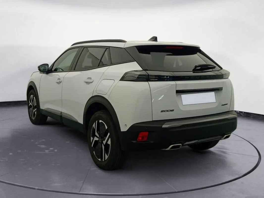 Vue 3/4 arrière gauche du Peugeot 2008 Hybrid blanc avec barres de toit et jantes alliage 17 pouces.