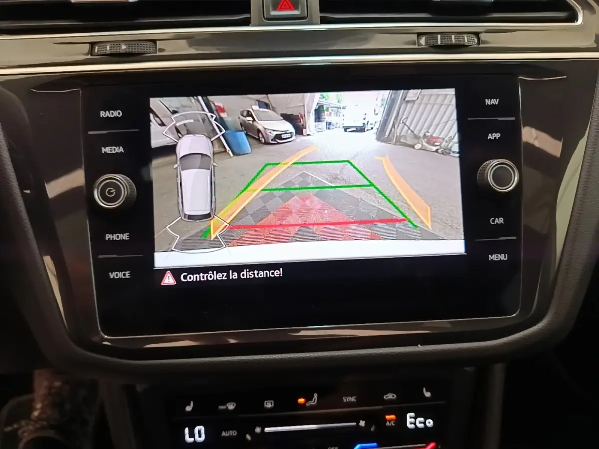 Écran tactile central montrant la caméra de recul avec guidage dynamique sur un Volkswagen Tiguan blanc.