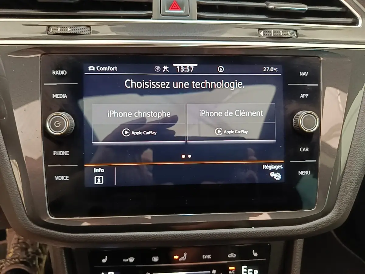Écran tactile central du Volkswagen Tiguan blanc 2023 montrant la connexion Apple CarPlay avec deux iPhones.