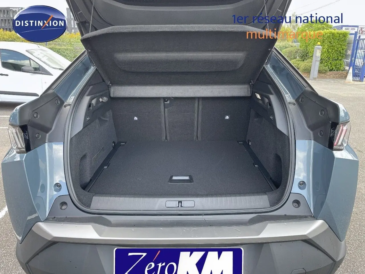 Coffre ouvert du Peugeot 3008 Hybrid 136ch Allure bleu Ingaro métal vu de l'arrière, montrant un espace de chargement spacieux.