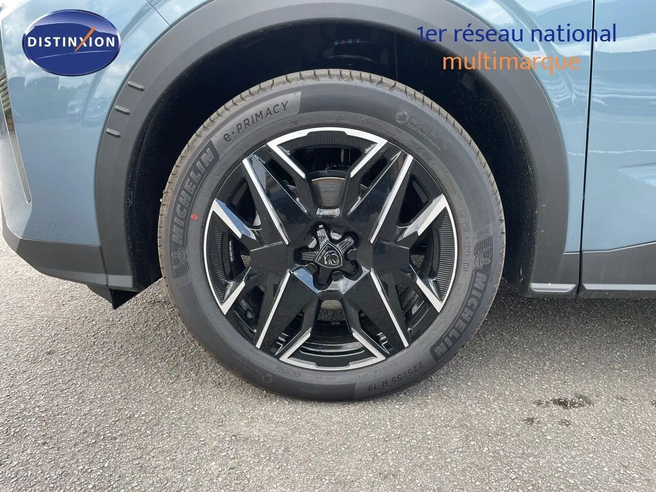 Gros plan sur la roue avant gauche du Peugeot 3008 Hybrid 2025 en bleu Ingaro Métal avec jante noire et argentée.