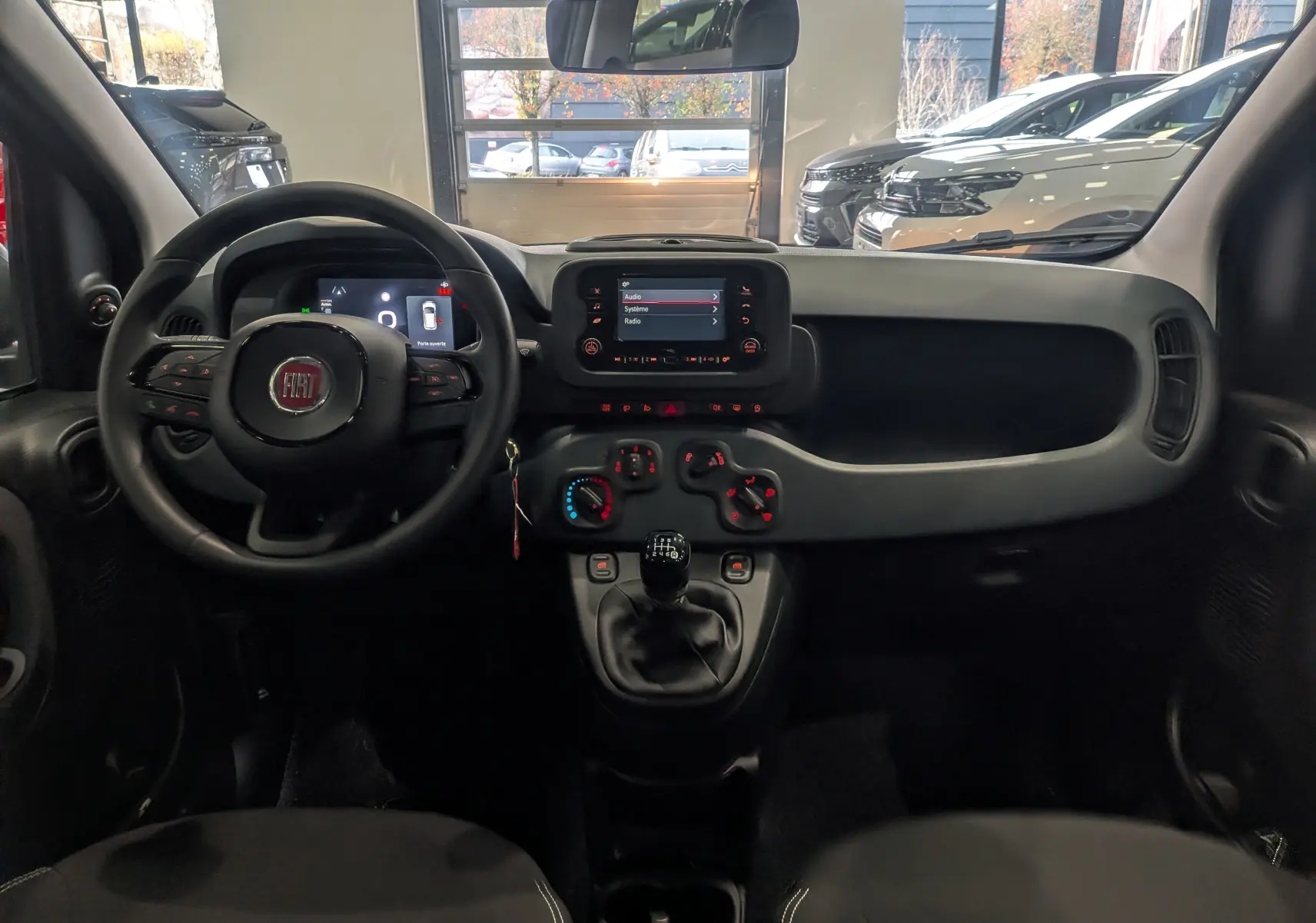 Vue intérieure avant de la Fiat Panda 1.0 Hybrid 2025 en Noir Cinéma, avec tableau de bord et volant multifonction.